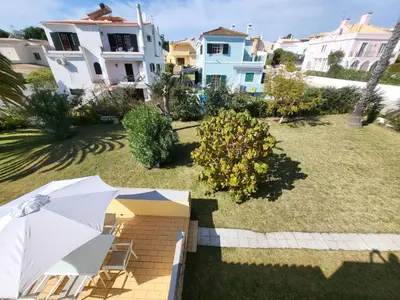 a patio with an umbrella in a yard with houses at Vilamoura Beach Villa with Private Pool in Quarteira