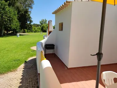 a white building with a table and chairs and an umbrella at Vilamoura Beach Villa by nature with Olympic Pool in Quarteira