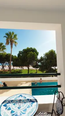 a window with a view of a pool and palm trees at Carteia Mar by FHR frente Mar & piscina in Quarteira