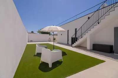a patio with two white chairs and an umbrella at Sirius House in Guia