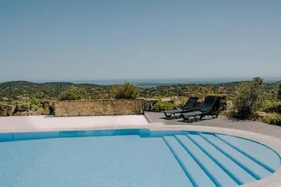 a swimming pool with two chairs and a view at Villa Monte dos Agostos by Boaz Rentals in Santa Bárbara de Nexe
