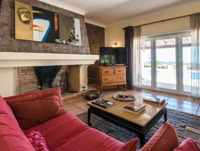 a living room with a red couch and a fireplace at Villa Monte dos Agostos by Boaz Rentals in Santa Bárbara de Nexe