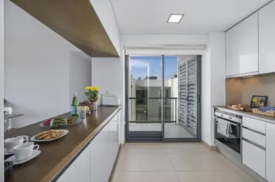 a kitchen with white cabinets and a large window at Sol e Mar in Quarteira