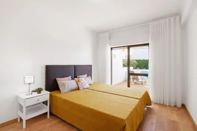 a white bedroom with a bed with a yellow bedspread at Apartment Zeza in Albufeira