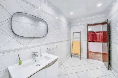 a white bathroom with a sink and a mirror at Villa Garbino in Albufeira