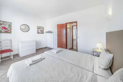 a bedroom with a large bed and a red chair at Villa Alecrim in Albufeira