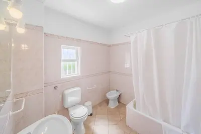 a white bathroom with a toilet and a sink at Villa Alecrim in Albufeira