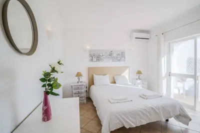 a white bedroom with a bed and a mirror at Villa Alecrim in Albufeira