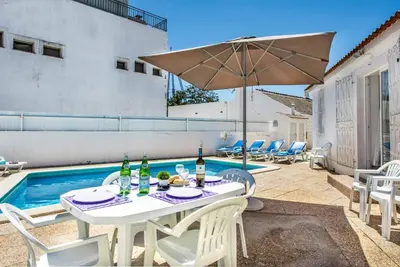 a swimming pool with blue and white chairs next to a building at Villa Oahu in Albufeira