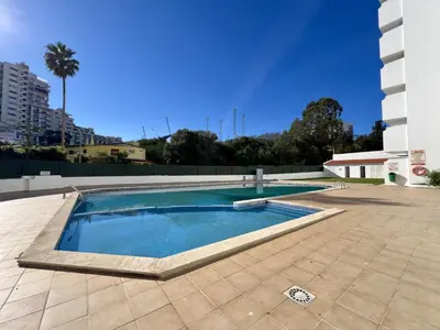 a swimming pool in the middle of a tile patio at Albufeira Town Apartment With Pool by Homing in Albufeira