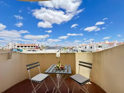 a balcony with two chairs and a table with fruit on it at Albufeira Central 9 by Homing in Albufeira