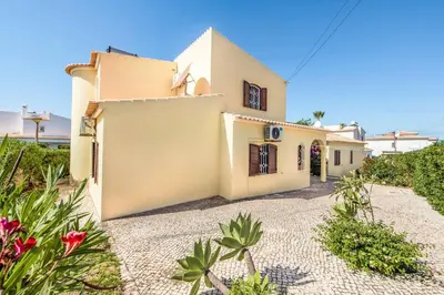 a large white house with a yard with flowers at Villa Pardal in Albufeira