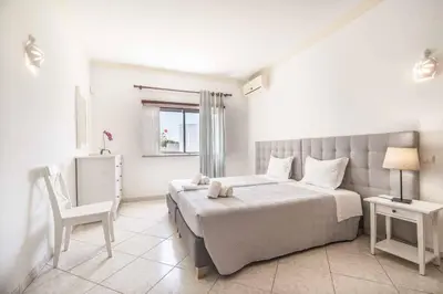a white bedroom with a bed and a chair at Villa Palawan in Galé