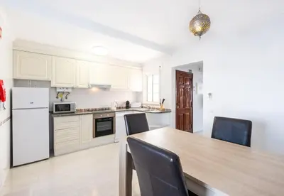 a kitchen with white cabinets and a table and chairs at Apartment Nidio - Great Location in Albufeira