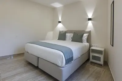 a bedroom with a large white bed and a night stand at Solar Mendonca in Faro