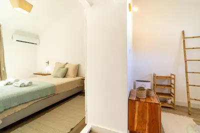 a white bedroom with a bed and a ladder at Falésia Sunset Villa by HelloVacations in Albufeira