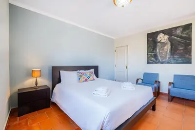 a bedroom with a white bed and a blue chair at Villa Laranja in Guia