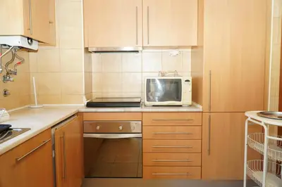 a kitchen with wooden cabinets and a microwave at Sacada Apartment in Guia