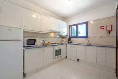 a white kitchen with white cabinets and a window at Casa Rita by Sunnyway in Olhos de Água