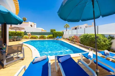 a swimming pool with blue chairs and umbrellas at Villa Cristina 15 in Albufeira