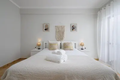 a white bedroom with a bed with towels on it at ISA - Quarteira in Quarteira