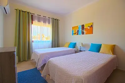 a hotel room with two beds and a window at Dinita Apartamentos in Albufeira