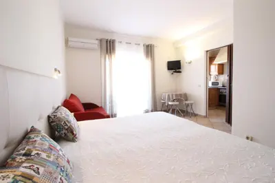 a bedroom with a white bed and a living room at Dinita Apartamentos in Albufeira