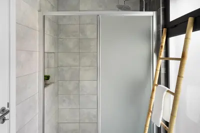 a shower with a glass door in a bathroom at Faro Nony Apartment by Get Your Stay in Faro