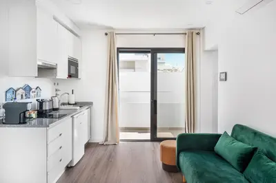 a living room with a green couch and a kitchen at Faro Nony Apartment by Get Your Stay in Faro