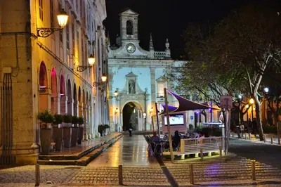a city street at night with a building with a clock tower at Residencial A Doca in Faro