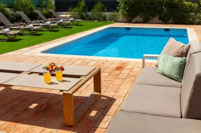 a pool with a table with two drinks on it at Villa Bellegarde by Algarve Vacation in Albufeira
