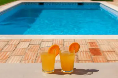 two glasses of orange juice sitting next to a swimming pool at Villa Bellegarde by Algarve Vacation in Albufeira
