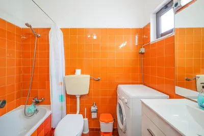 an orange tiled bathroom with a toilet and a sink at SeaView apartment by MOJE Holiday in Albufeira