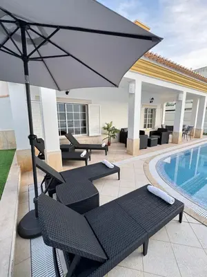 a patio with chairs and an umbrella next to a pool at Villa Bonita Guesthouse Albufeira Old Town in Albufeira