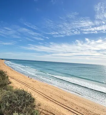 a beach with people walking on the sand and the ocean at Villa Bonita Guesthouse Albufeira Old Town in Albufeira