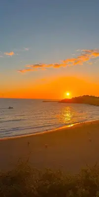 a sunset on a beach with the sun setting over the ocean at Villa Bonita Guesthouse Albufeira Old Town in Albufeira