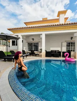 a woman is kneeling in front of a swimming pool at Villa Bonita Guesthouse Albufeira Old Town in Albufeira