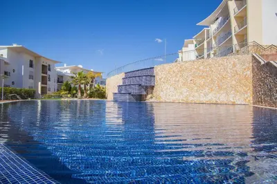 a swimming pool with blue water in front of some buildings at Sea View Penthouse in Albufeira in Albufeira