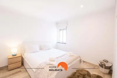 a white bedroom with a bed and a window at #089 Largo Escola by Home Holidays in Albufeira