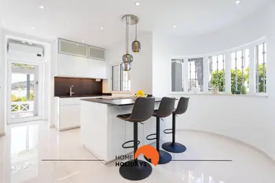 a kitchen with white cabinets and black counter stools at #221 Cerro Grande by Home Holidays in Albufeira