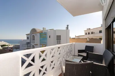 a balcony with chairs and a table and a building at 404 - Oura - 2 Bedroom - Sea View in Albufeira