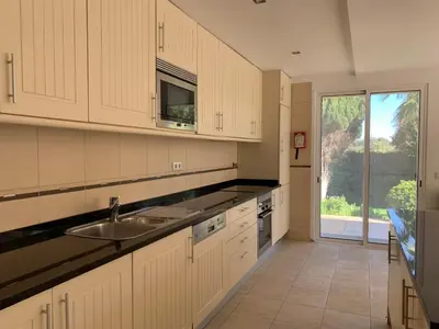 a kitchen with white cabinets and a sink at Villa Sofia in Almancil