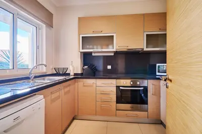a kitchen with wooden cabinets and a sink and a window at Apartment Sol de Verão mit Pool in Guia