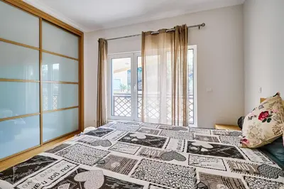 a bedroom with a bed with a view of a balcony at Apartment Sol de Verão mit Pool in Guia