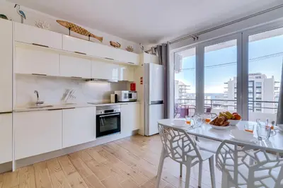 a kitchen with white cabinets and a table with chairs at Noah House, 2 bdr apartment with sea view in Quarteira
