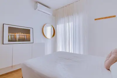 a white bedroom with a bed and a mirror at Apartment with Rooftop and work space in Quarteira in Quarteira