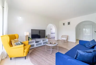 a living room with a blue couch and a tv at Villa Vilamoura NATURE GREEN GOLF AND POOL in Quarteira