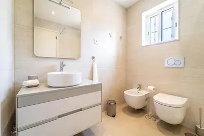 a bathroom with a sink and a toilet and a mirror at Villa Vilamoura NATURE GREEN GOLF AND POOL in Quarteira