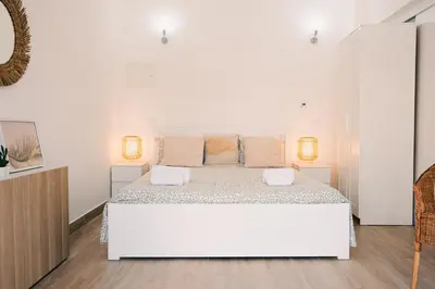 a white bedroom with a large white bed with two lamps at Studio LUMINEUX et CALME à Vilamoura in Quarteira