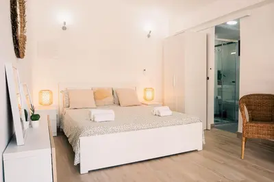 a white bedroom with a white bed and a chair at Studio LUMINEUX et CALME à Vilamoura in Quarteira